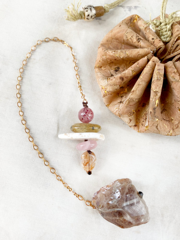Pendulum with Smokey Quartz and a cairn of crystals in warm tones